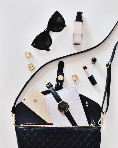 a woman, sunglasses, a black bag, a wristwatch, lipsticks, rings, iPhone