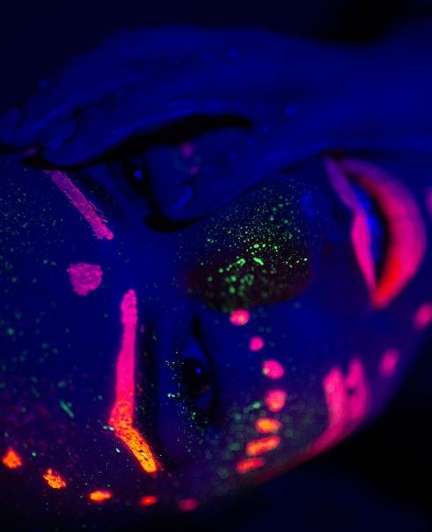 a close up of the face of a woman with glow in the dark paint
