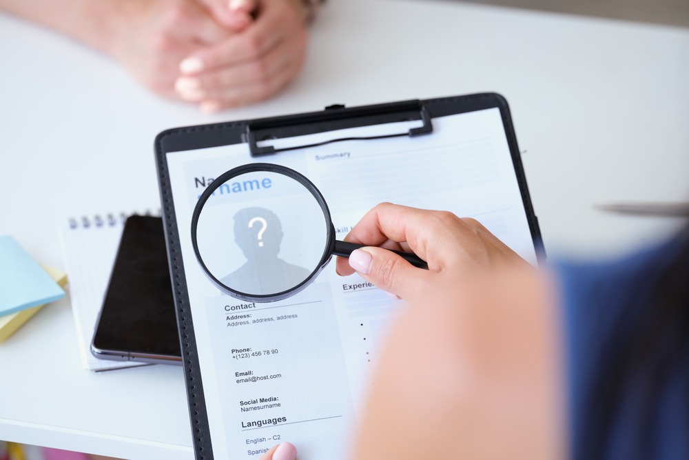 Employer looking at worker resume with magnifying glass closeup