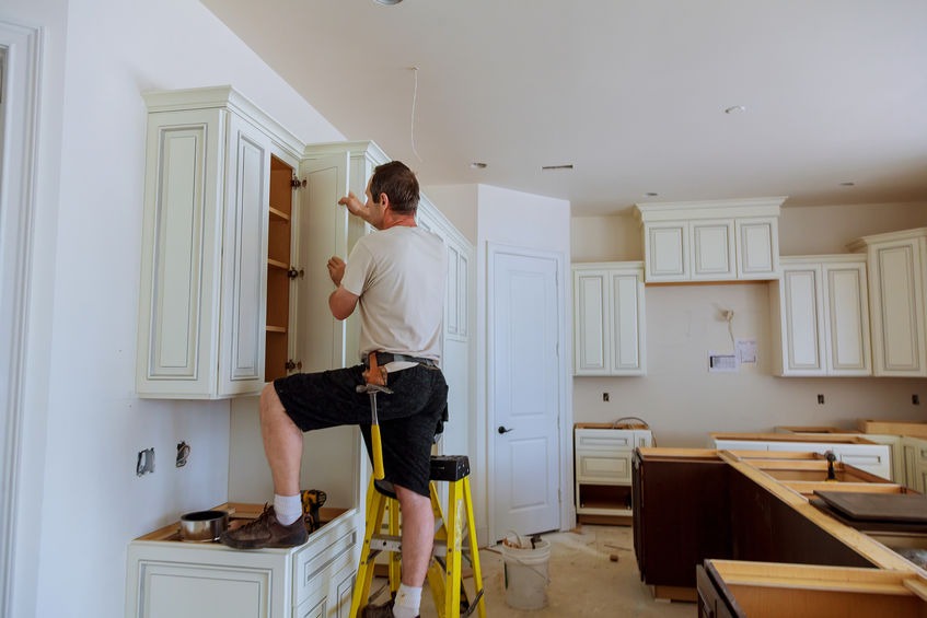 Installation of kitchen. Worker installs doors to kitchen cabinet.