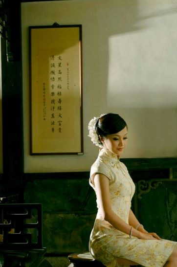a woman sitting down wearing a cheongsam