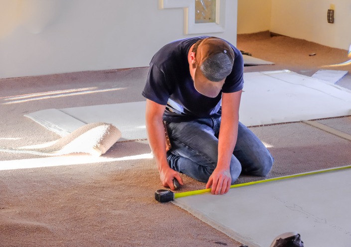 Carpenter measuring new rugs before installation