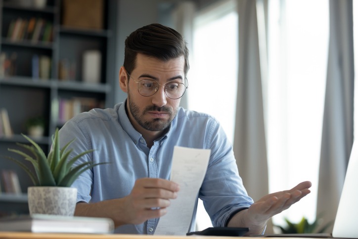 Confused shocked man looking at receipt, checking bills