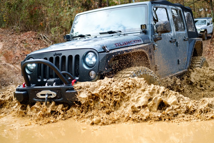 Modified Jeep Rubicon JK driving through mud.