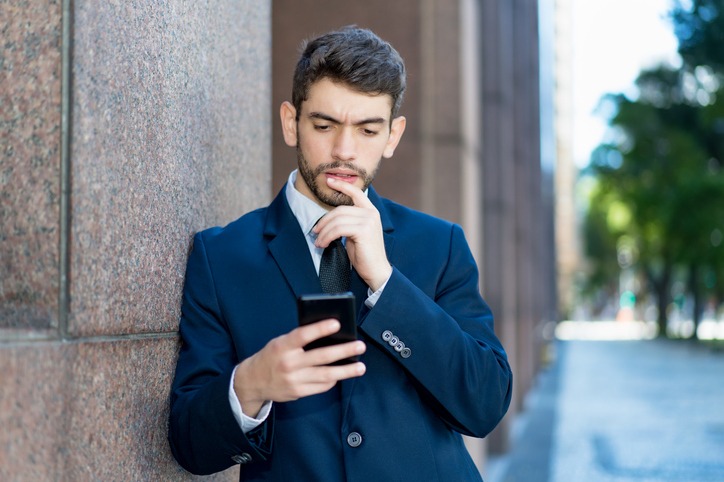 Hipster businessman with beard and suit looking at phone