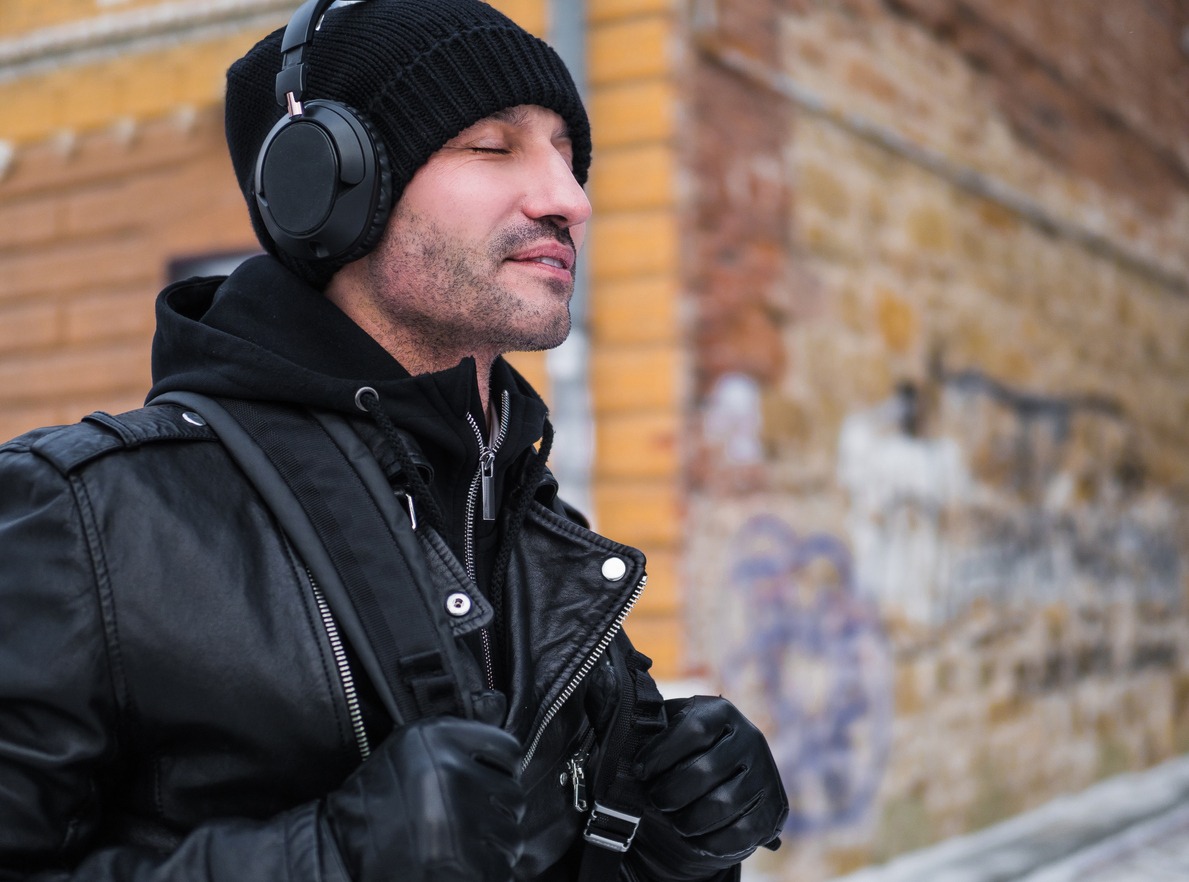 a man walking by the street in winter time and listening to the music via headphones