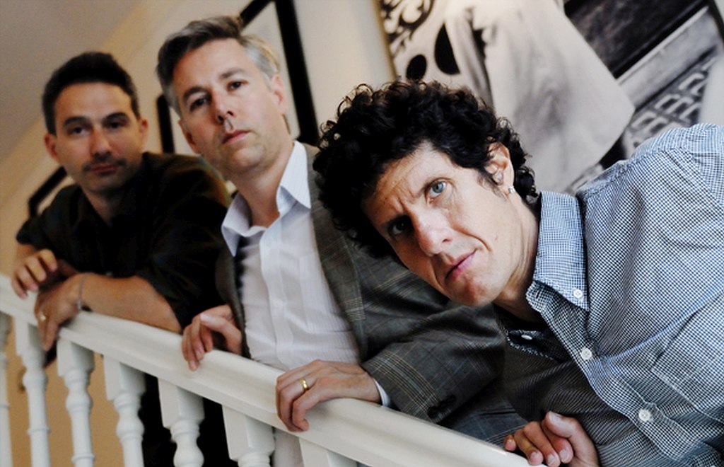 A group of three men on a stairwell in front of a light background