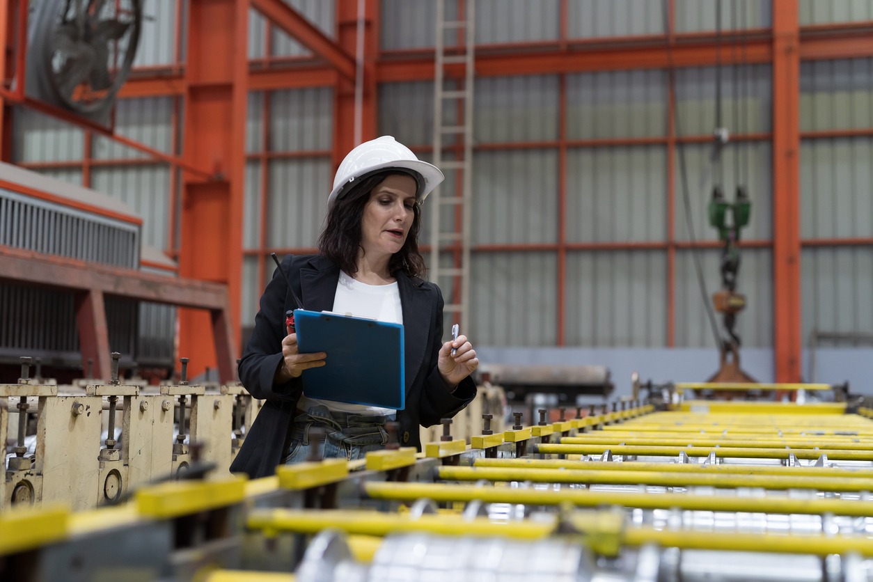 Female factory worker working and using clipboard inspecting quality of production