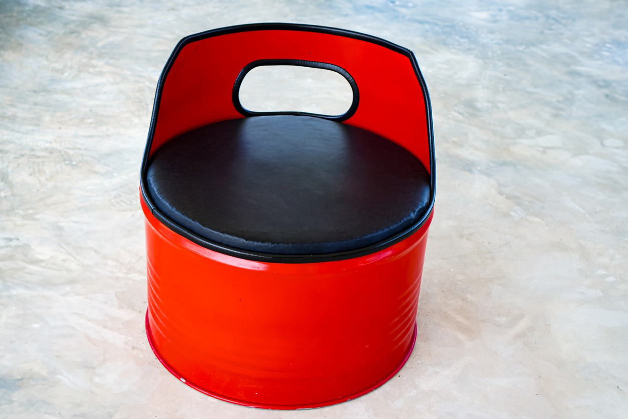 Picture of a red chair made from used oil drums that has been modified with leather seats to make it a relaxing chair for indoors or outdoors