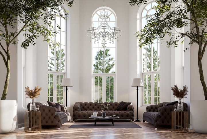 living room has wooden floors, decorated with elegant brown fabric sofas and large plant pots, arched window to admire nature