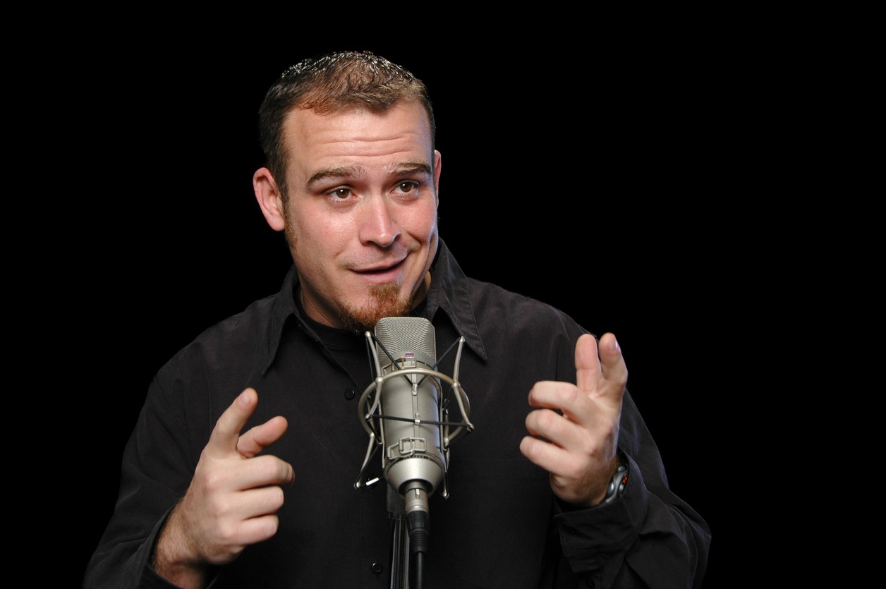 A male stand-up comedian is talking on stage