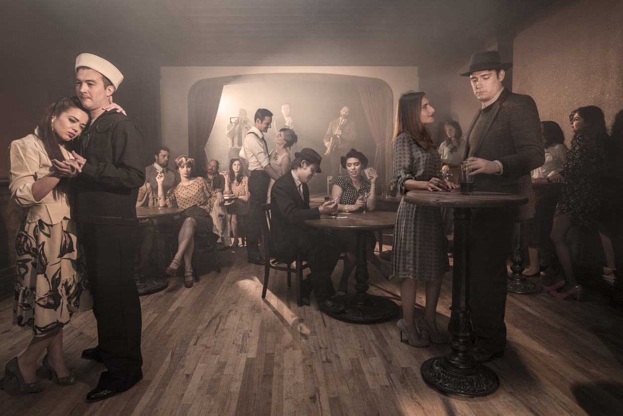 Men and women in classy dress, with styles from a 1940s, post-Prohibition-era speakeasy