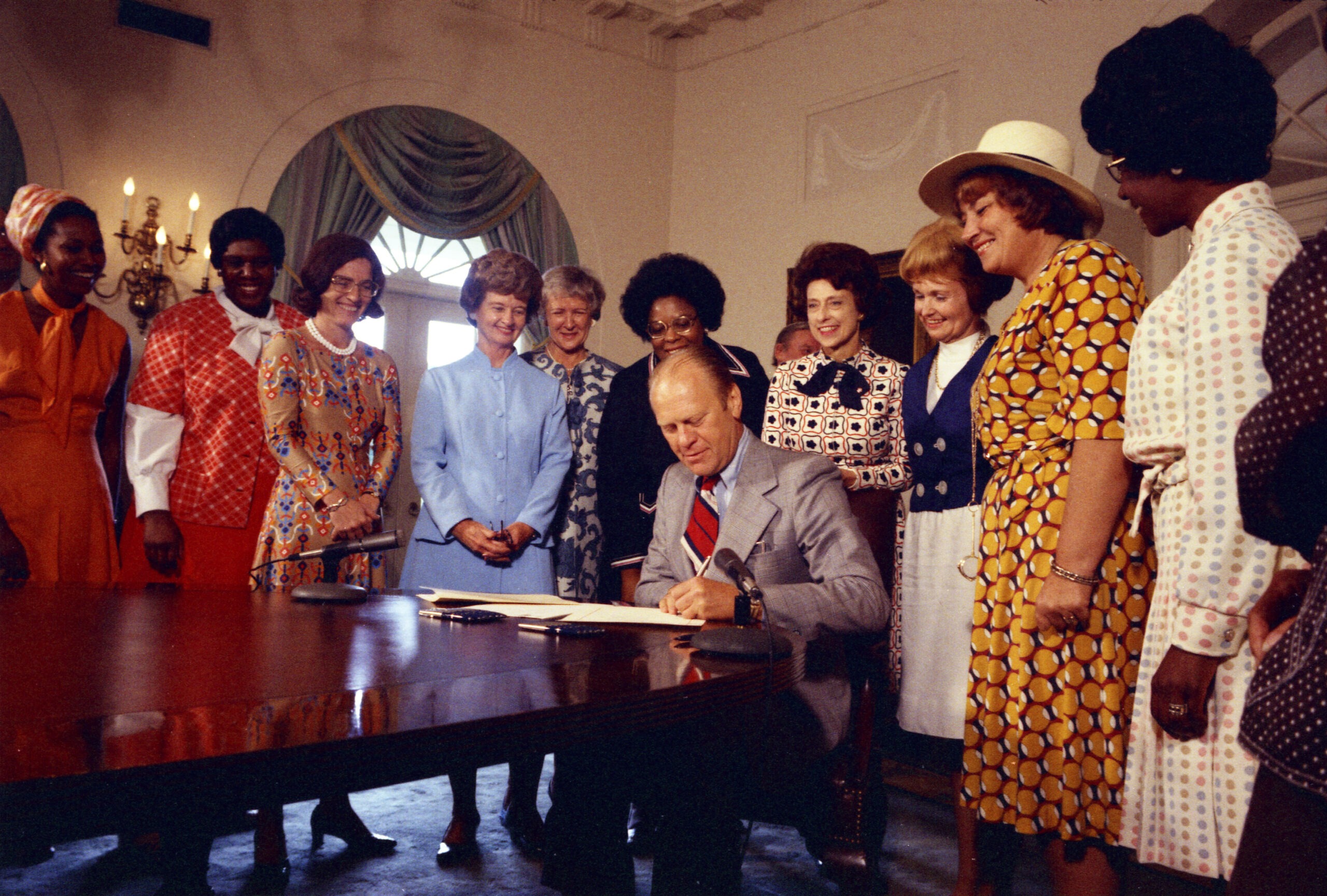 women surrounding the president signing the Proclamation on Women's Equality Day