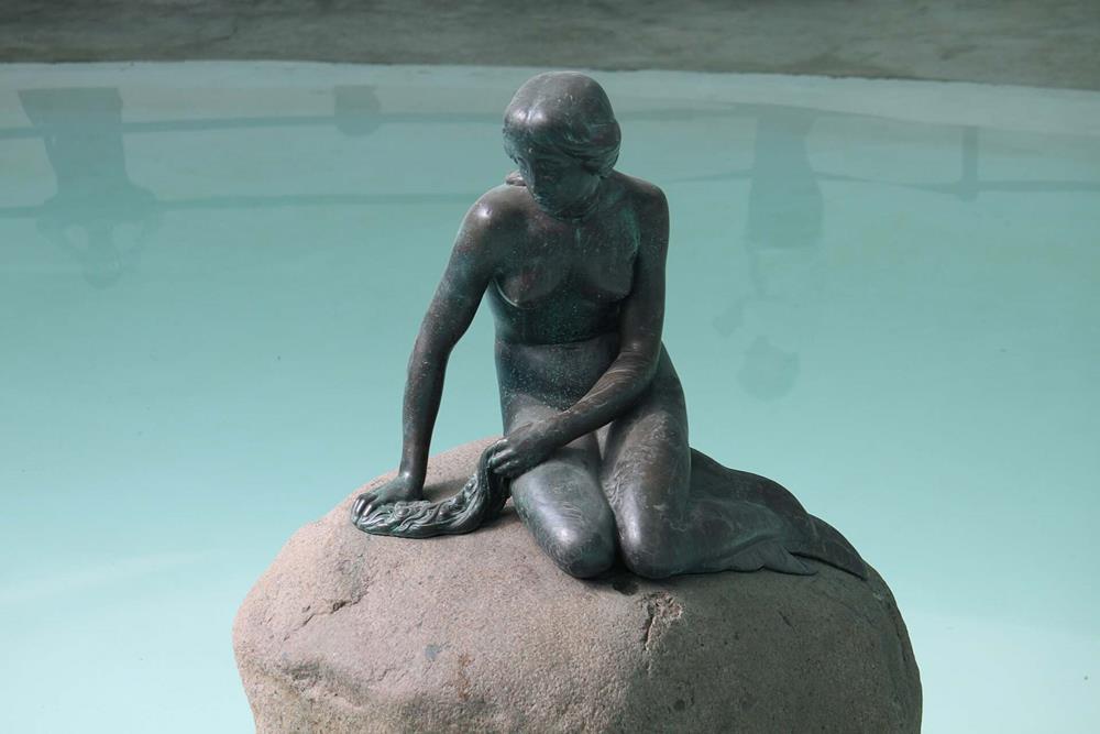 A statue of a mermaid on a stone