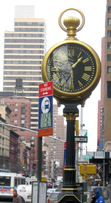 Big clock near a street sign