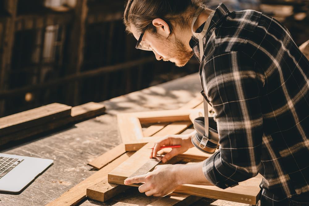 Carpenter Joiner man making wooden furniture in wood workshop