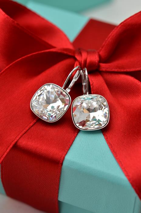 Diamond earrings attached to a red bow on a gift box