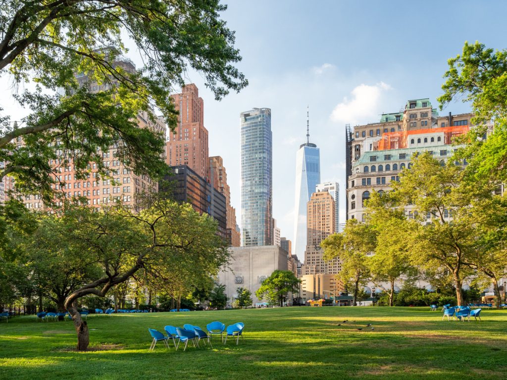 A scenic view of empty blue chairs in green Battery Park in New York City, United States